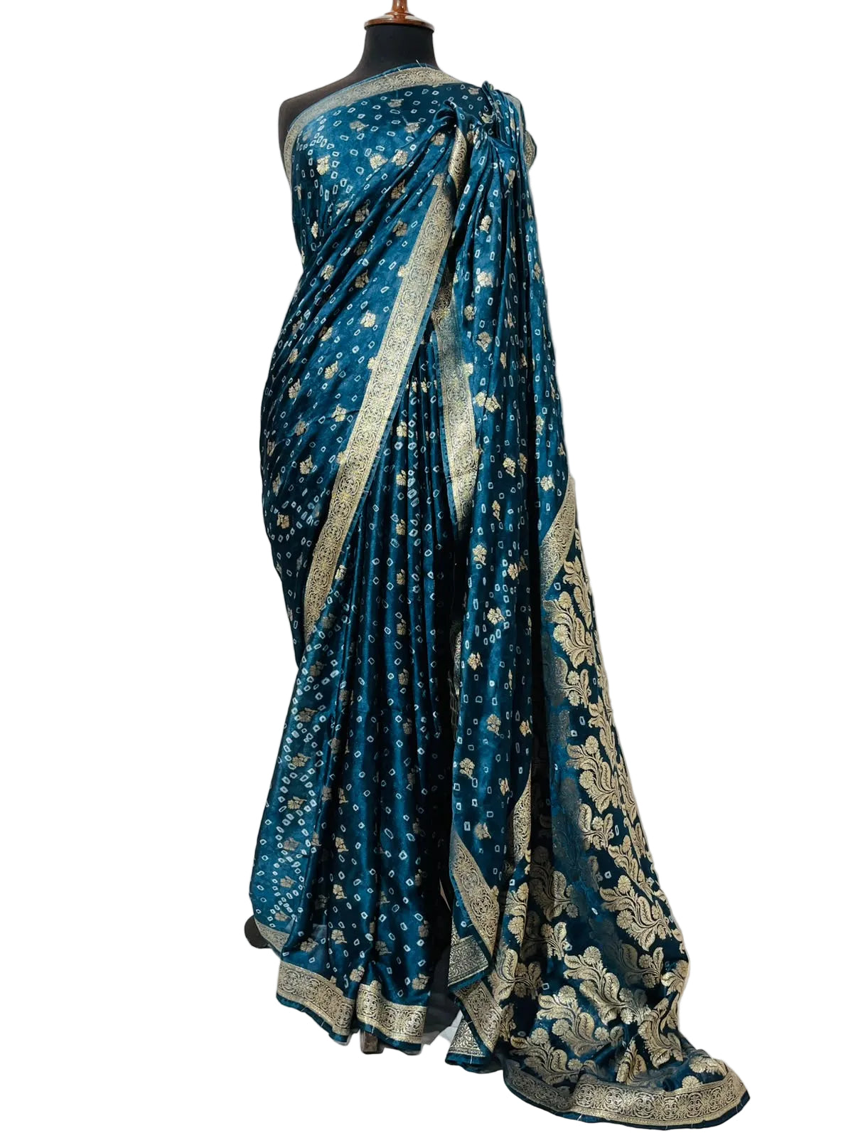 A teal blue sari with intricate gold floral patterns and a wide gold border, displayed on a black mannequin against a white fabric backdrop.