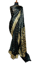 A black silk saree with intricate gold zari floral and geometric patterns, draped on a black mannequin torso against a white fabric backdrop.