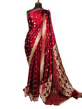 A deep red silk saree with gold zari floral patterns and borders, draped on a black mannequin torso against a white fabric backdrop.