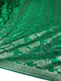A close-up of a rich green brocade fabric with intricate metallic gold floral and paisley patterns and a decorative border.