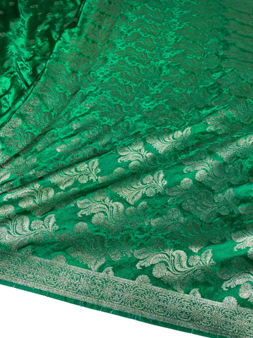 A close-up of a rich green brocade fabric with intricate metallic gold floral and paisley patterns and a decorative border.